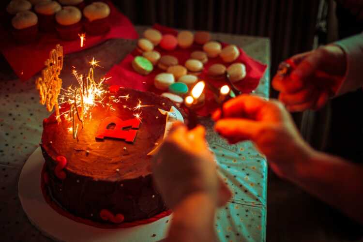 person holding lighted candle on clear glass container