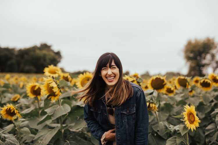 smiling woman standing beside sunflowers